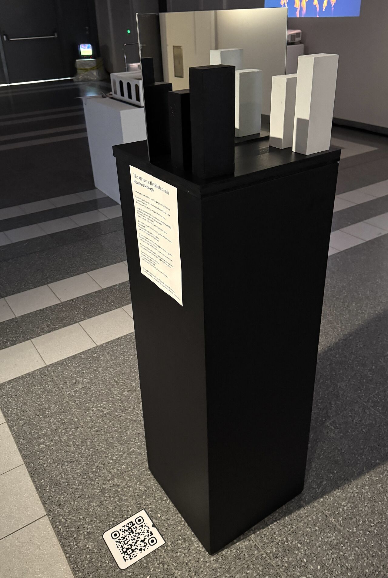 After the Name installation presented in an exhibition space, with a central mirror and black and white sculptural forms