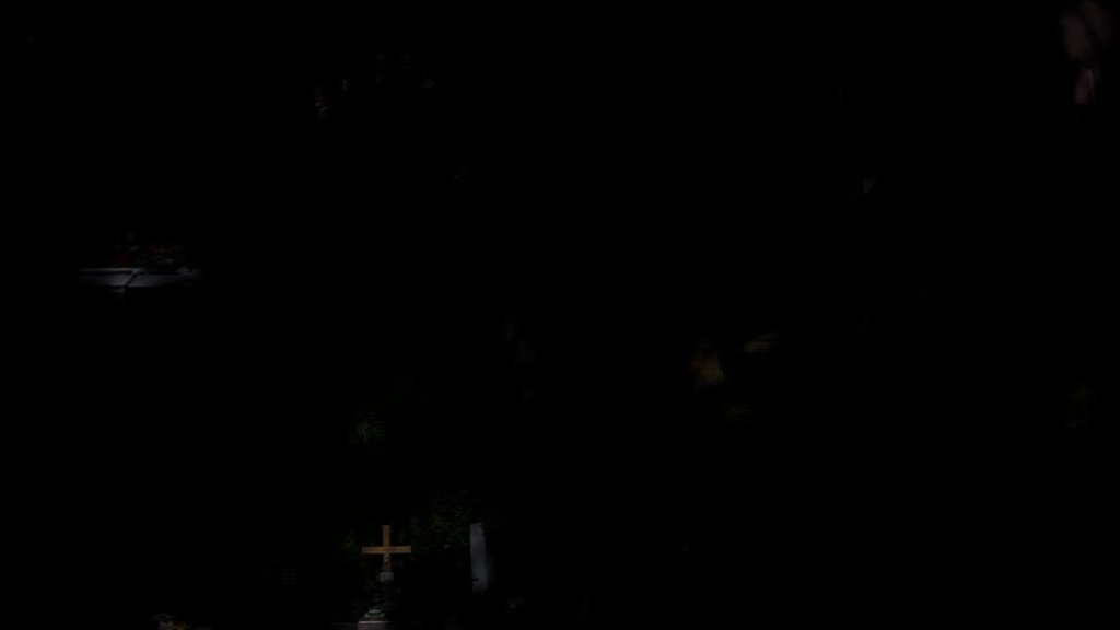 Dark cemetery at night with a cross